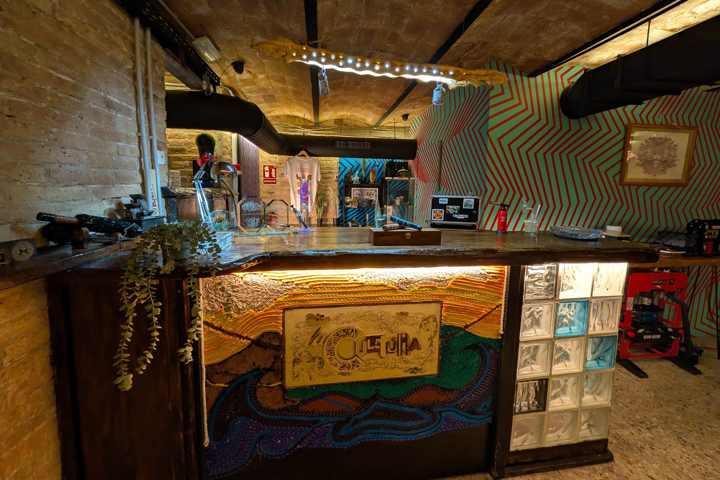 Barområdet i cannabisklubben La Cultura med konstnärlig disk och livfull väggdesign i Barcelona